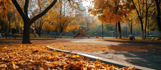 Empty playground roundabout surrounded by fallen autumn leaves in park. Creative Banner. Copyspace image - obrazy, fototapety, plakaty