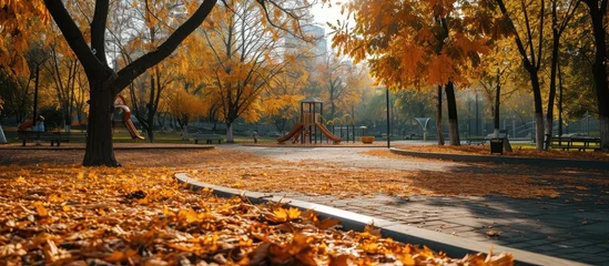 Deurstickers Empty playground roundabout surrounded by fallen autumn leaves in park. Creative Banner. Copyspace image © HN Works