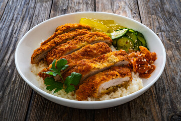 Torikatsu - crispy Japanese chicken cutlet with white rice and marinated vegetables on wooden table
