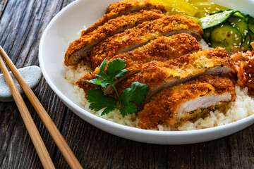 Torikatsu - crispy Japanese chicken cutlet with white rice and marinated vegetables on wooden table
