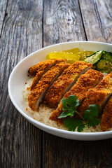 Torikatsu - crispy Japanese chicken cutlet with white rice and marinated vegetables on wooden table
