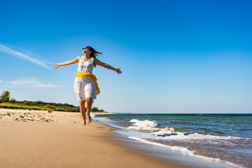 Obraz na płótnie Canvas Beautiful mid adult woman walking, running on sunny beach 