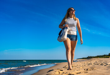 Beautiful mid adult woman walking on sunny beach
