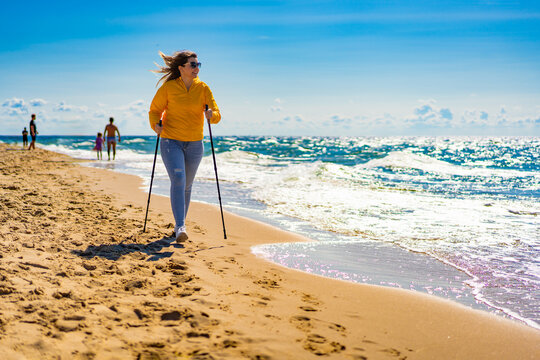 Nordic walking - beautiful woman exercising on beach
