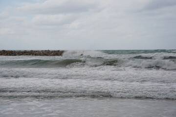 Strong currents and waves in the sea. Waves successfully crash into the stone breakwater.