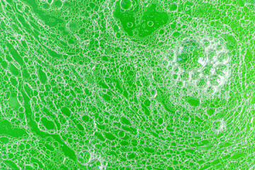 abstact background foam bubbles on detergent and fat water emulsion in green tones close up