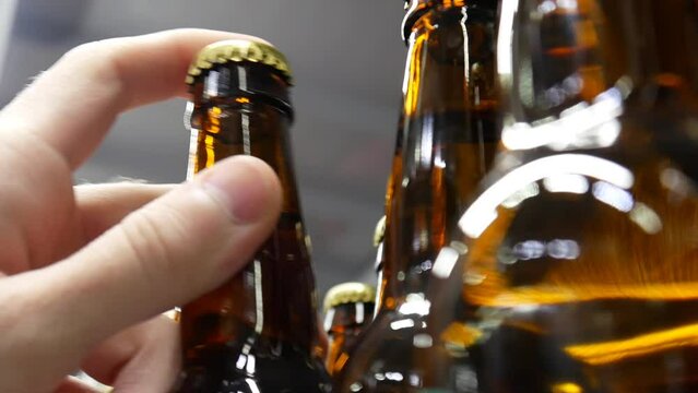 Close-up of a row of glass bottles of beer and a buyer's hand takes one