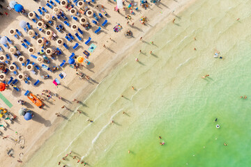 Aerial view on beach, people and umbrellas. Vacation and adventure. Europe, Mediterranean Sea. Top view from drone at beach and azure sea. View on the coast from drone.