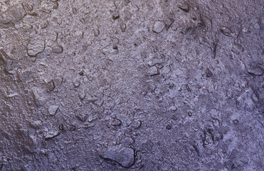 Close up of muddy puddle with small stones on wet surface. Background texture