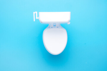 Flatlay picture of toilet bowl on blue background.