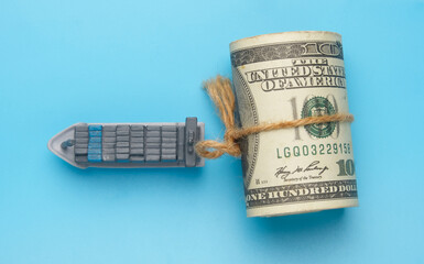 Flatlay picture of vessel miniature with roll fake money on blue background. Shipment cost