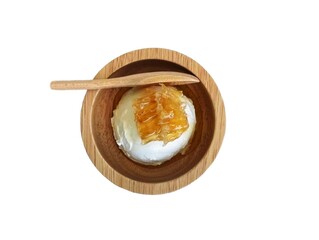 The white background in the picture is a brown wooden cup with white ice cream and a golden-yellow honey cube. A brown wooden spoon is placed in the cup nearby. There is a jar of honey tied to the mou