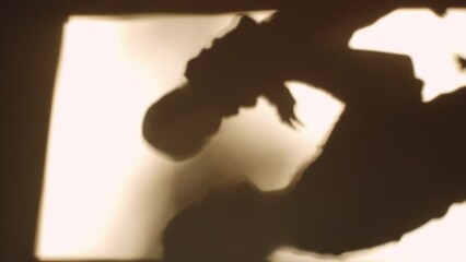 Vertical video of shadow unknown caring young mother holding little baby son or daughter on white wall at home during warm sunset or sunrise. Fun family spending time together