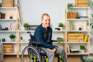 Happy disabled man in wheelchair smiling in the living room - obrazy, fototapety, plakaty