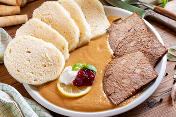 Svickova na smetane ( beef in sour cream sauce) served with knedlik (bread dumpling) on the table, traditional Czech cuisine