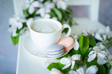 Coffee and macaroons among delicate white flowers apple tree. Delicate morning coffee with a wonderful spring-summer mood. Soft selective artistic focus