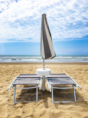 Two sunbeds and an umbrella closed in front of the sea