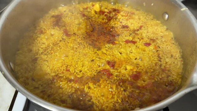 Pilaf during preparation in stainless steel pot on stove top