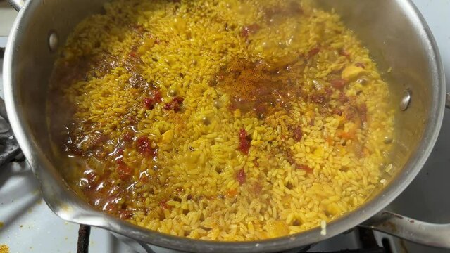 Pilaf during preparation in stainless steel pot on stove top