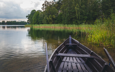 Wooden boat with oars on the shore of a forest lake. Summer holidays