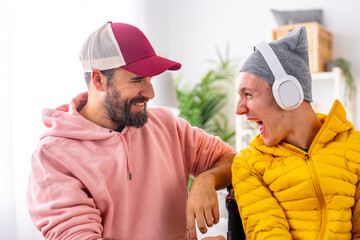 Excited disabled man listening to music using headphones with friend
