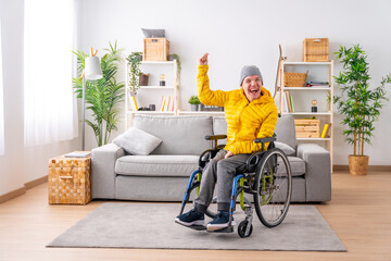 Disabled man in wheelchair celebrating raising fist at home