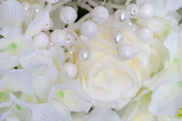 Gentle light background of white roses and beads. Close-up shooting, soft focus