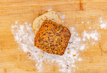 Baked and fresh sliced bread roll with flour on a wooden board