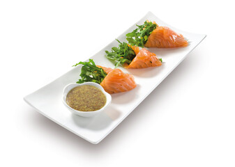 Rollitos de salmón ahumado con rùcula  y salsa , sobre fondo blanco. Smoked salmon rolls with arugula and sauce, on a white background.