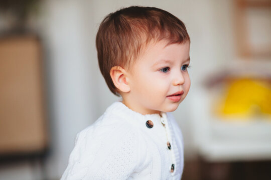 Adorable dreamy little boy toddler with blue eyes standing indoors