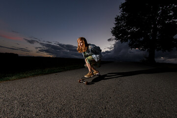 Young girl riding a longboard on the road, looking ahead in concentration