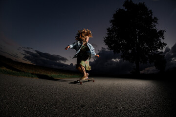 Young girl is riding a longboard on the road, her arms are out to the sides