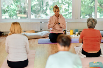 Obraz premium A group of senior women engage in various yoga exercises, including neck, back, and leg stretches, under the guidance of a trainer in a sunlit space, promoting well-being and harmony
