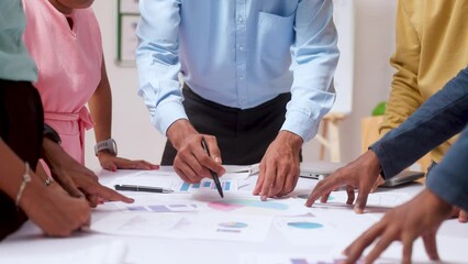 Group of unrecognizable corporate startup employees discussing from charts during meeting at office - concept of team meeting, data analysis and review.