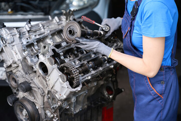 Specialist is repairing large auto part in auto repair shop