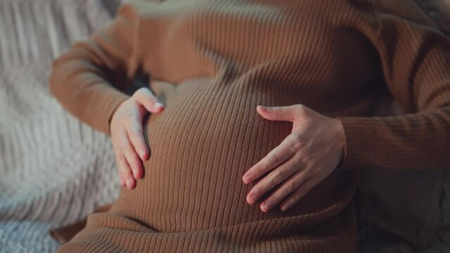 Pregnant woman doing heart gesture with hands on belly at home, Love, motherhood a pregnancy concept.