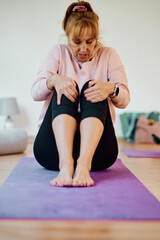 In a sunlit space, a senior woman gracefully practices rejuvenating yoga, focusing on neck, back, and leg stretches, embodying serenity and well-being