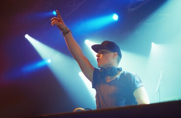 Man, headphones and stage lighting for music performance or techno, festival or fans. Dj, hand and...