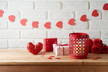 Valentine's day concept with lantern, gift box and heart shapes garland over brick wall background