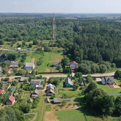 Cell tower in rural area surrounded by forest. Satellite communication and Internet in a countryside settlement, village. Transmitter of cellular communication.