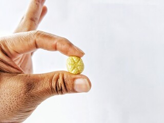 Hand holding a piece of candy, on a white background