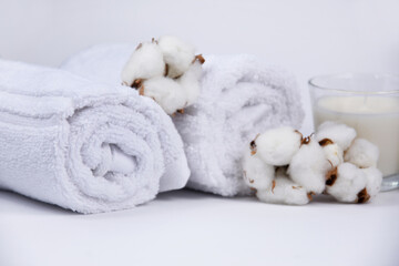 Fototapeta na wymiar White towels and cotton flowers spa still life stock photo images. Spa and wellness setting with towels, candles and cotton flowers on white background. White spa-concept stock images