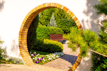 Brick round Japanese arch in the summer garden.