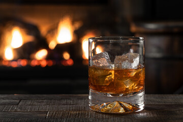 Glass of whiskey with burning fireplace in background