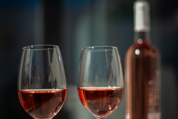 Two elegant glasses of rosé wine clinking in a relaxed atmosphere, with the rosé bottle in the background.