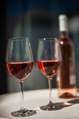 Two elegant glasses of rosé wine clinking in a relaxed atmosphere, with the rosé bottle in the background.