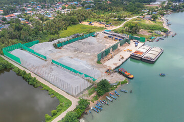 Aerial top view of concrete cement factory industry with sea. Electricity tower building in energy, transportation, logistic or environment concept. Manufacturing workshop station.