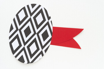 machine-cut paper oval with black and white diamantine pattern and red paper tags or elements on white