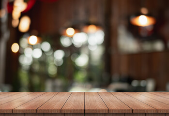 Empty wooden table top with lights bokeh on blur restaurant background.