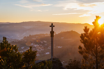 Silhouette one of the numerous medieval cruceiros (calvary) in Ourense against an orange sky. - 714068996